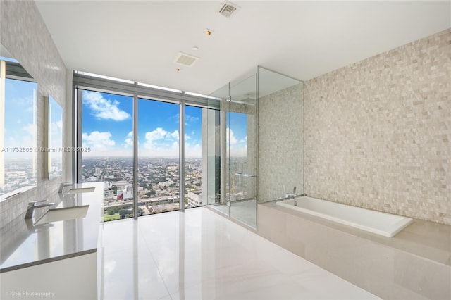 bathroom with a relaxing tiled tub, a wealth of natural light, and expansive windows