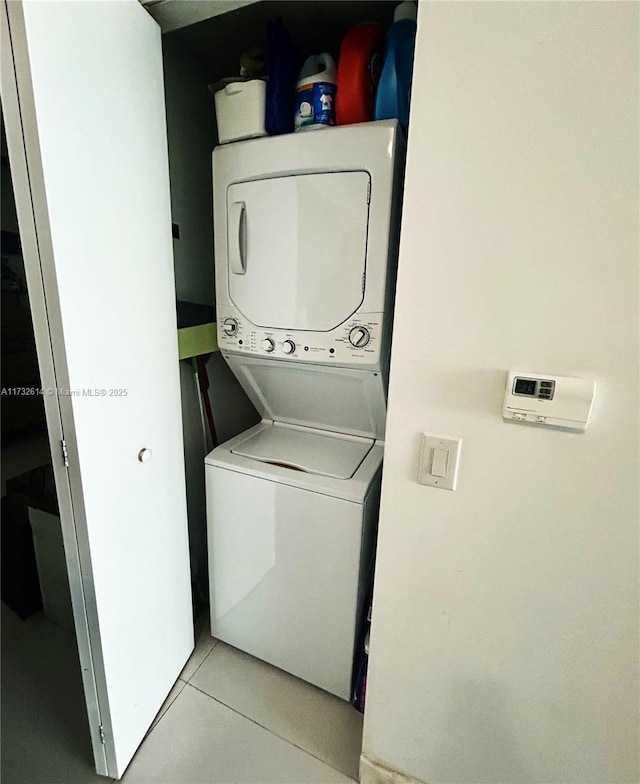 laundry area featuring stacked washer / drying machine and light tile patterned floors