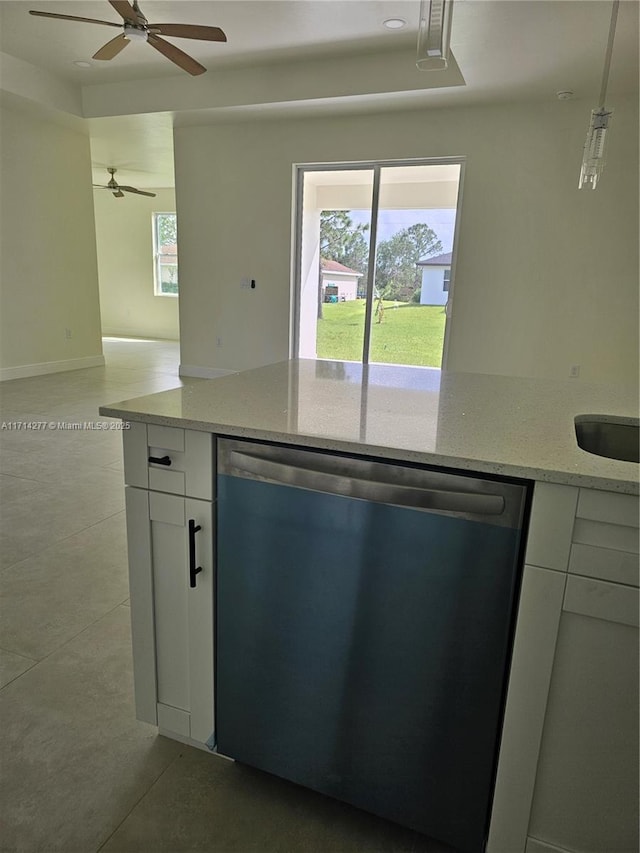 kitchen with pendant lighting, light tile patterned floors, white cabinetry, light stone counters, and stainless steel dishwasher