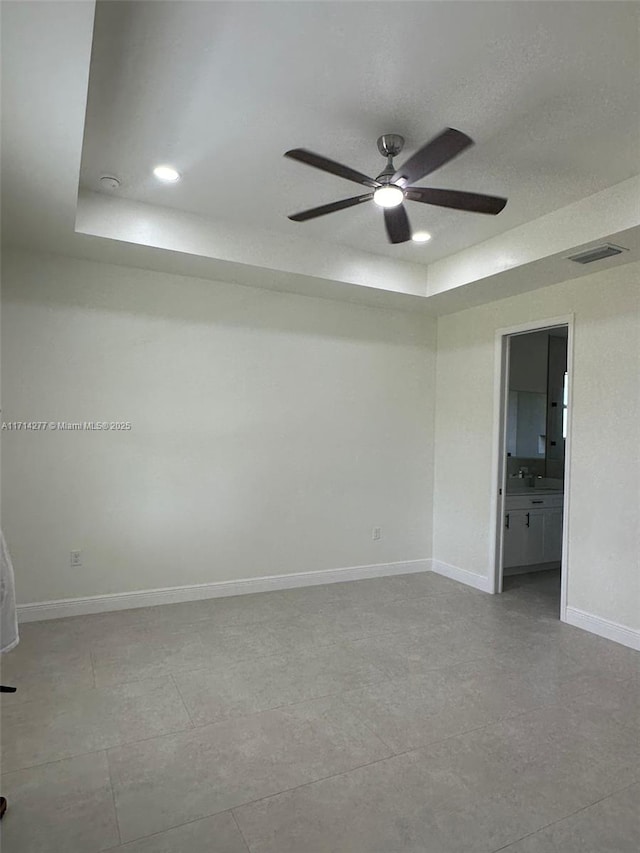 spare room featuring a raised ceiling and ceiling fan