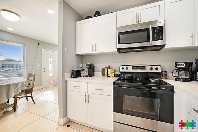 kitchen with appliances with stainless steel finishes, light tile patterned floors, and white cabinets