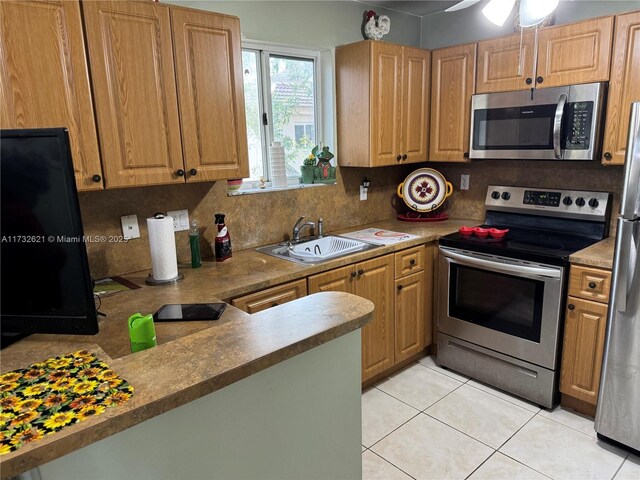 kitchen featuring tasteful backsplash, sink, light tile patterned floors, and appliances with stainless steel finishes