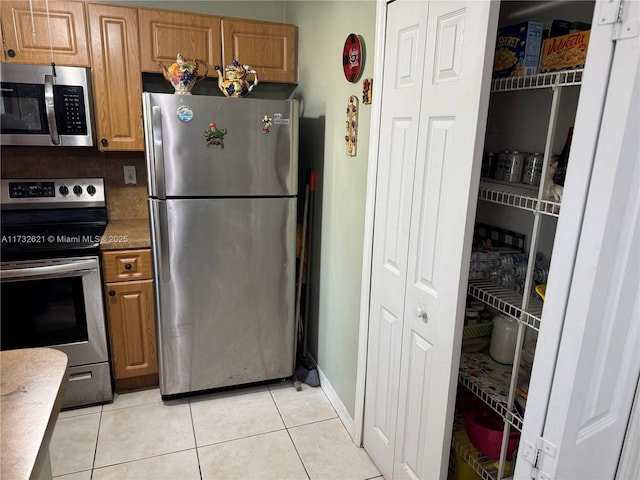 kitchen featuring tasteful backsplash, light tile patterned floors, and appliances with stainless steel finishes