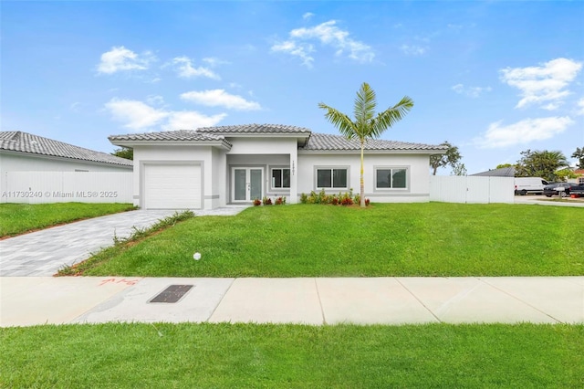 mediterranean / spanish house featuring a garage and a front lawn