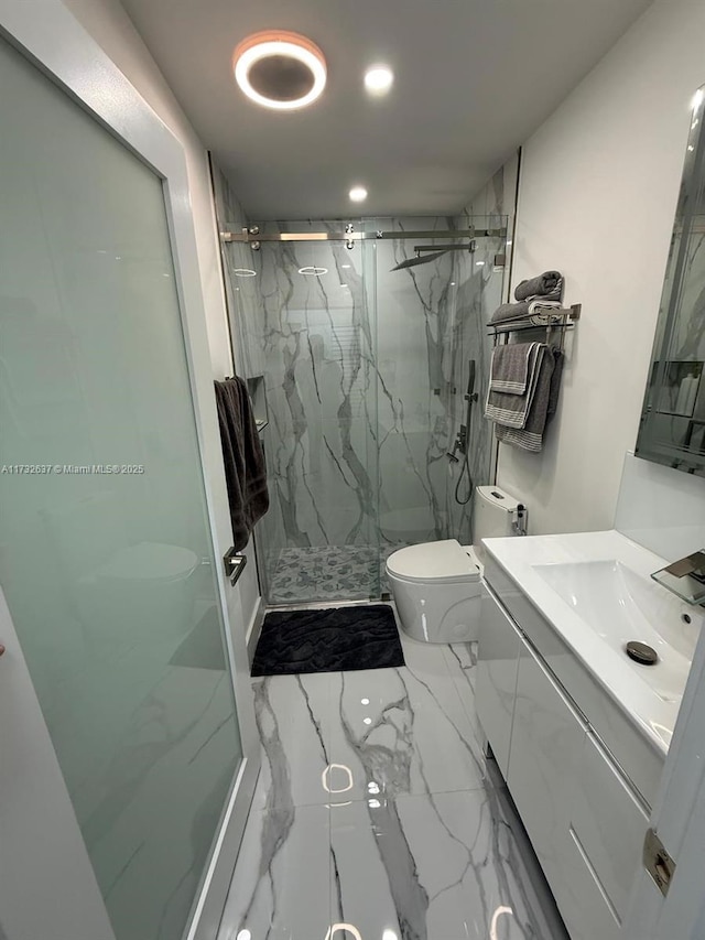 bathroom featuring vanity, toilet, and a shower with shower door