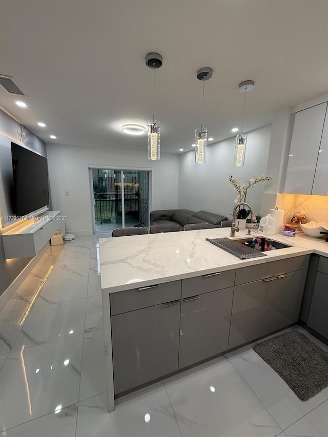 kitchen with gray cabinets, light stone countertops, sink, and decorative light fixtures