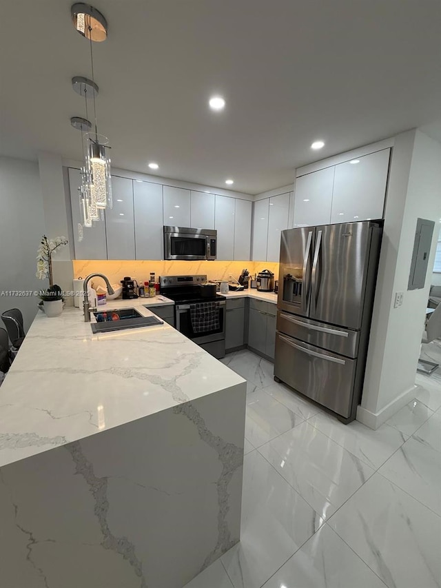 kitchen featuring pendant lighting, sink, appliances with stainless steel finishes, white cabinetry, and decorative backsplash