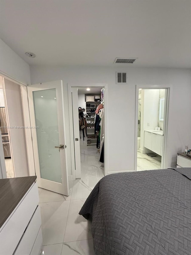 bedroom featuring a walk in closet, ensuite bathroom, and a closet