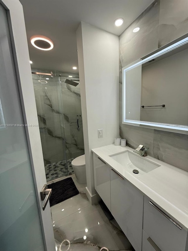 bathroom featuring vanity, an enclosed shower, and toilet