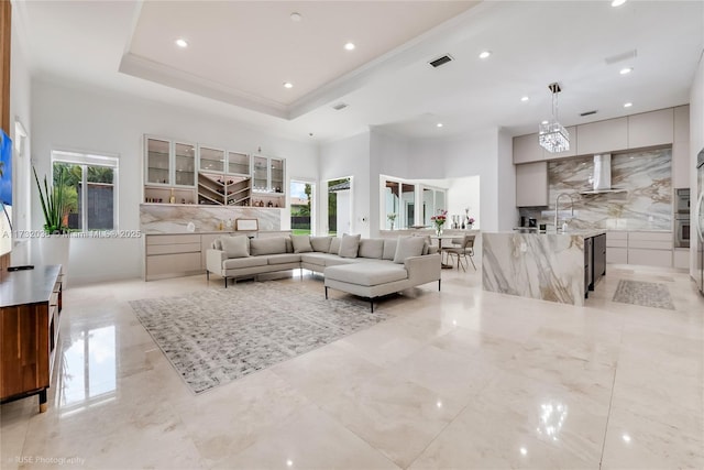 living room with sink, crown molding, and a raised ceiling