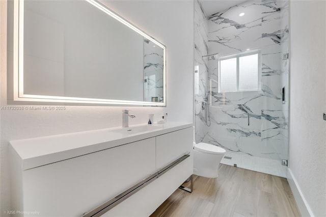 bathroom featuring hardwood / wood-style flooring, tiled shower, vanity, and toilet