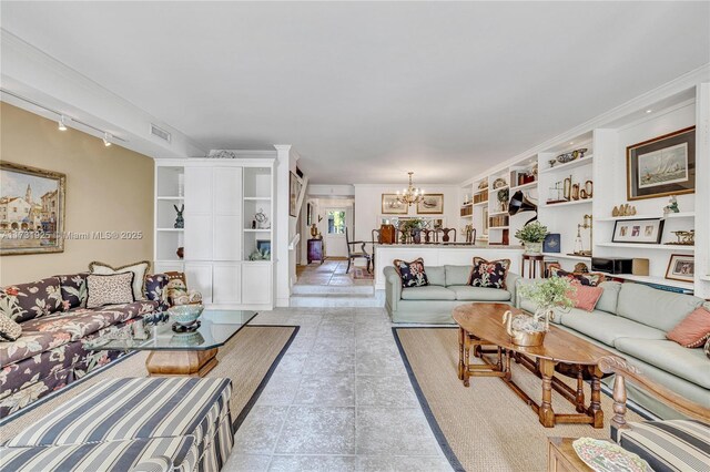 tiled living room with a notable chandelier, crown molding, track lighting, and built in shelves