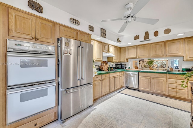 kitchen featuring sink, tile counters, stainless steel appliances, and ceiling fan