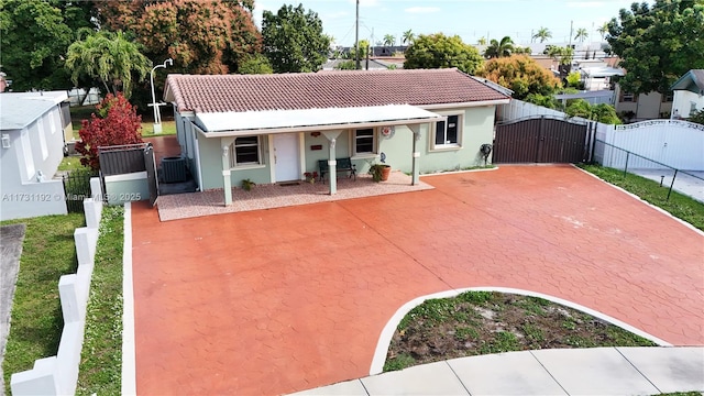 view of front of home with a gate, central AC, a tiled roof, and stucco siding