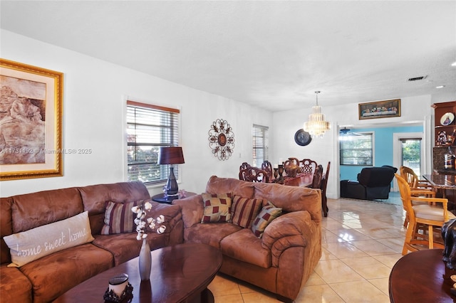 living area featuring light tile patterned floors, visible vents, and an inviting chandelier