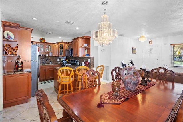 tiled dining space with sink, a notable chandelier, and a textured ceiling