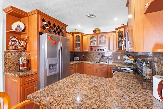 kitchen with appliances with stainless steel finishes, sink, backsplash, and kitchen peninsula