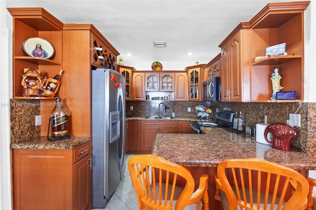 kitchen featuring appliances with stainless steel finishes, kitchen peninsula, decorative backsplash, and light tile patterned floors