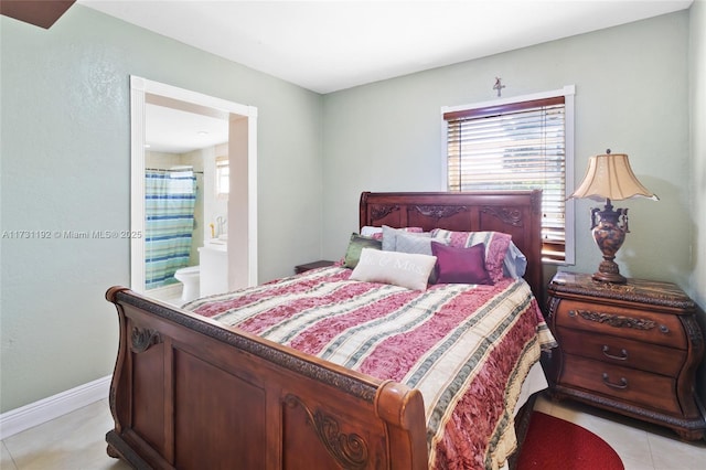 bedroom featuring ensuite bathroom, light tile patterned flooring, and baseboards