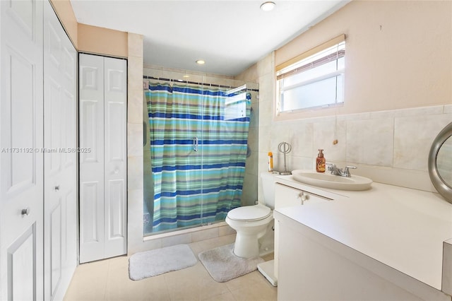 bathroom with a closet, tile patterned flooring, vanity, a shower stall, and tile walls