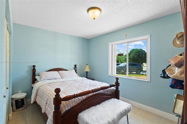 bedroom featuring light tile patterned flooring, a textured ceiling, and baseboards