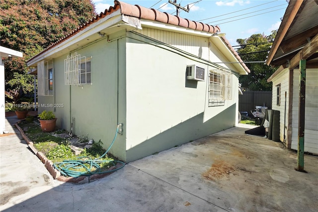 view of side of home featuring a patio, a wall mounted AC, and fence