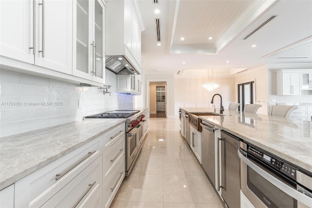 kitchen with white cabinetry, appliances with stainless steel finishes, a raised ceiling, and light stone countertops