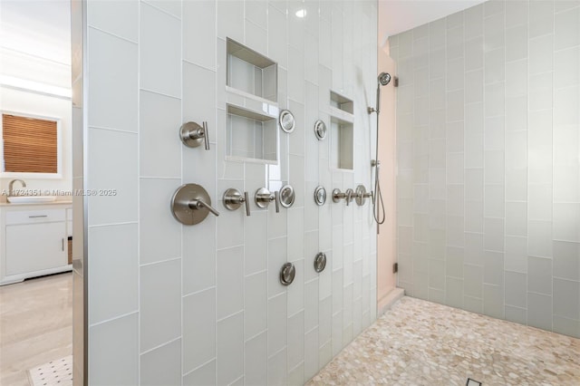 bathroom featuring tiled shower and sink