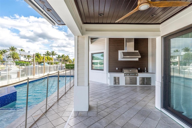 view of swimming pool with sink, a patio area, ceiling fan, a grill, and exterior kitchen