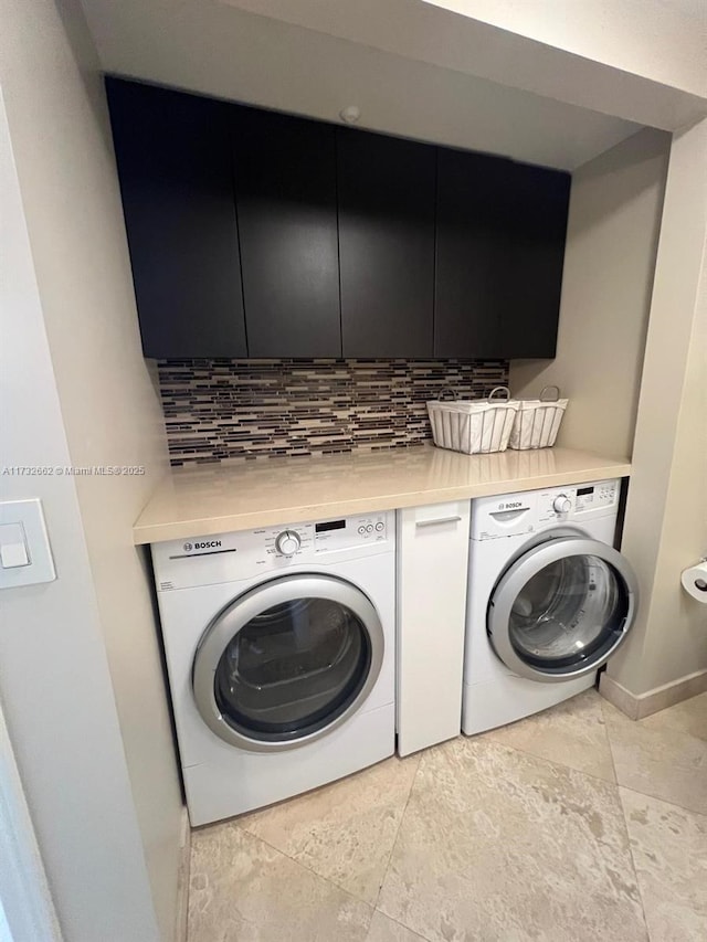 clothes washing area featuring cabinets and washing machine and clothes dryer