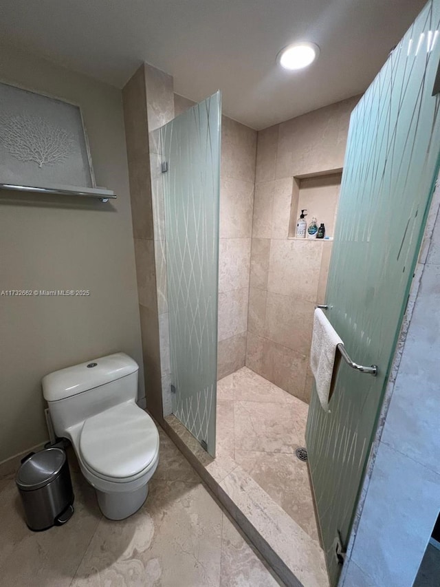 bathroom featuring toilet and a tile shower