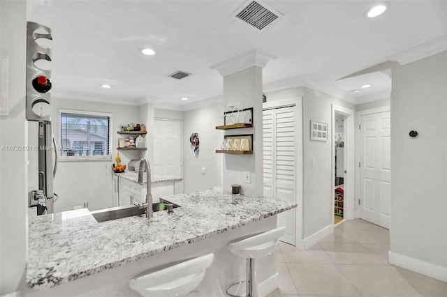 kitchen featuring sink, a kitchen breakfast bar, ornamental molding, kitchen peninsula, and light stone countertops