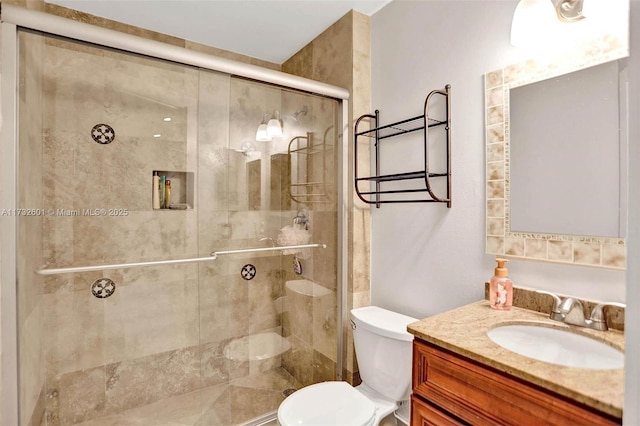 bathroom with a shower with door, vanity, and toilet