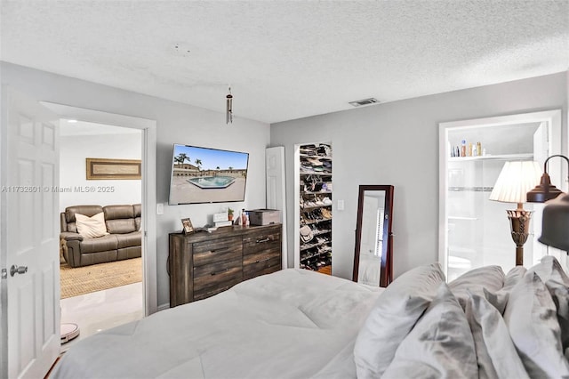 bedroom with ensuite bath, a walk in closet, a closet, and a textured ceiling