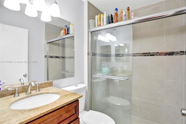 bathroom featuring vanity, a shower with shower door, and toilet