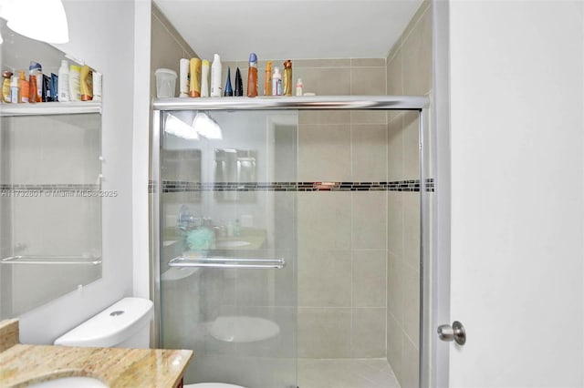 bathroom with vanity, toilet, and a shower with door