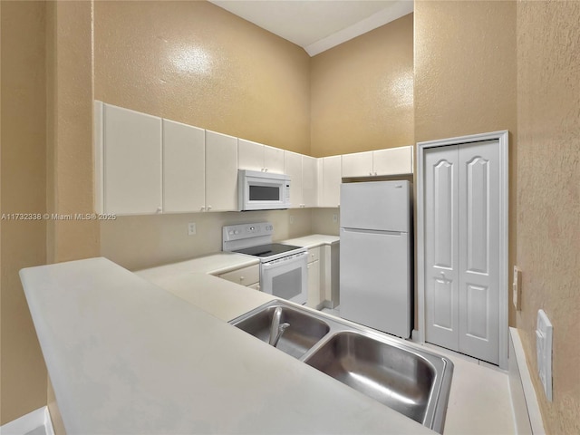 kitchen featuring white appliances, sink, and white cabinets