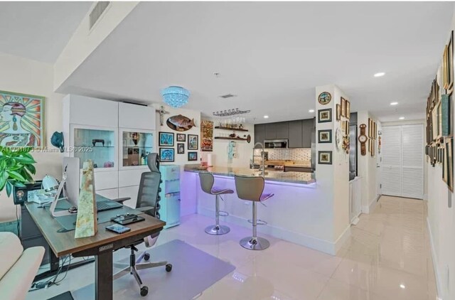 kitchen featuring backsplash, light tile patterned floors, a breakfast bar, and kitchen peninsula