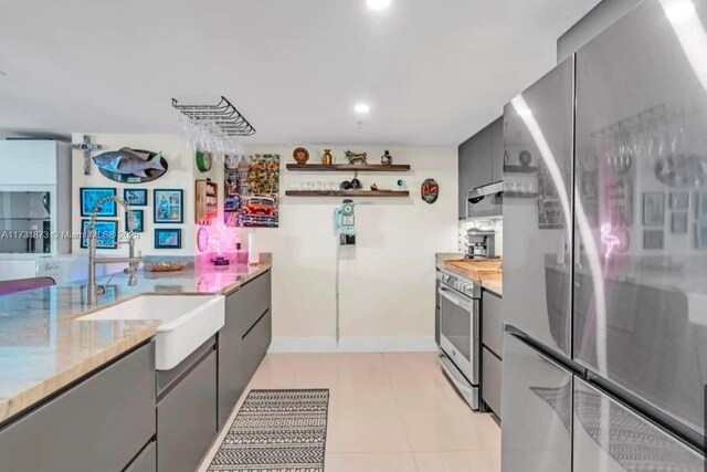 kitchen with light tile patterned flooring, stainless steel appliances, sink, and gray cabinetry