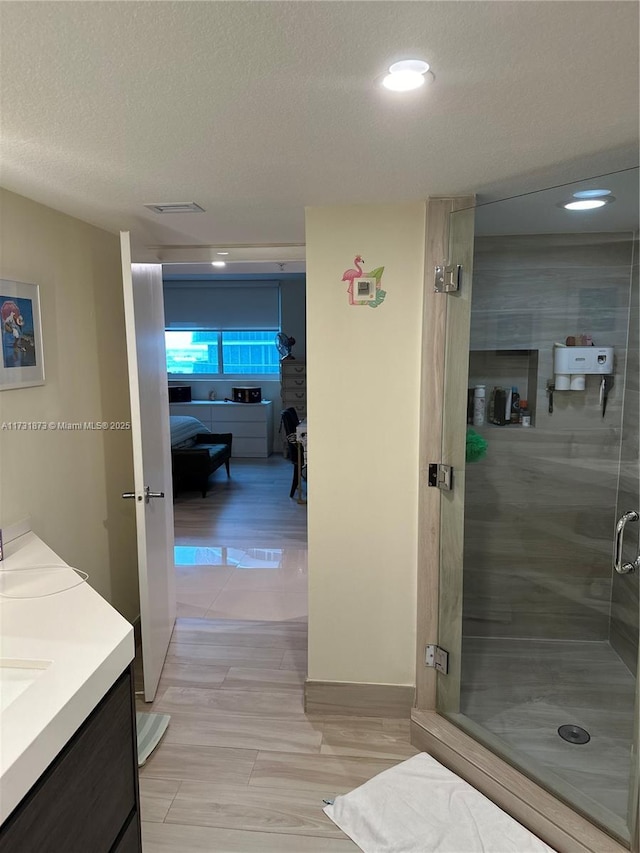 bathroom featuring vanity, a textured ceiling, and walk in shower