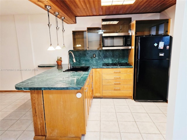 kitchen featuring dark countertops, stainless steel microwave, freestanding refrigerator, a sink, and wooden ceiling