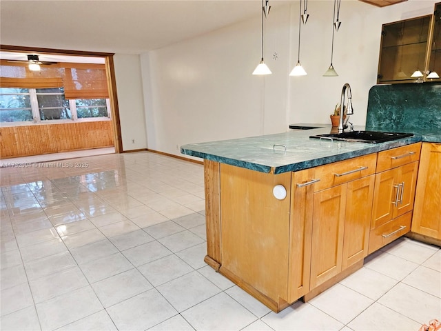 kitchen featuring light tile patterned floors, a ceiling fan, hanging light fixtures, a sink, and backsplash