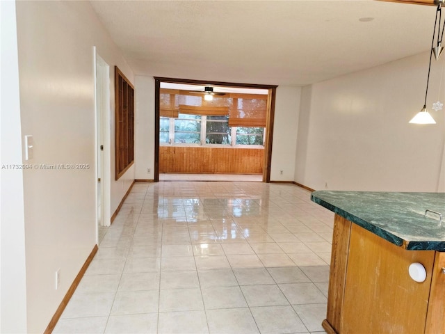 interior space with baseboards, a ceiling fan, and light tile patterned flooring