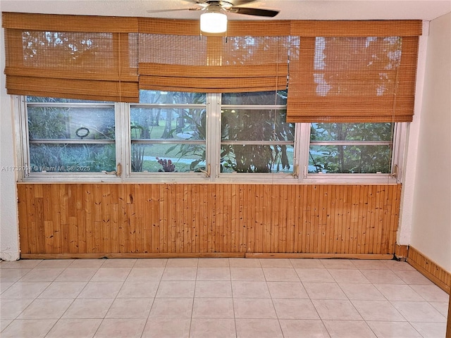 interior space with wooden walls, baseboards, and a ceiling fan