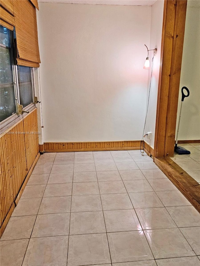 interior space with light tile patterned floors and wood walls