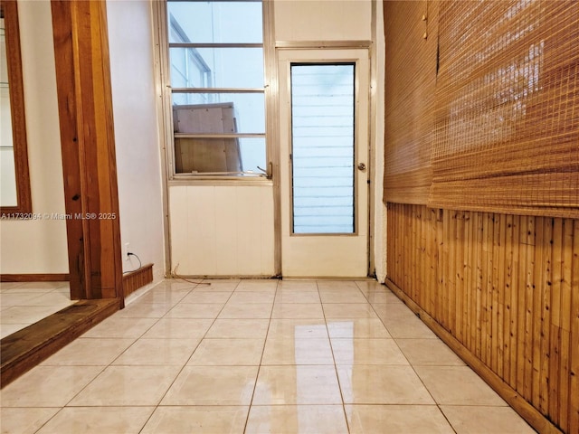 interior space with light tile patterned flooring and wooden walls