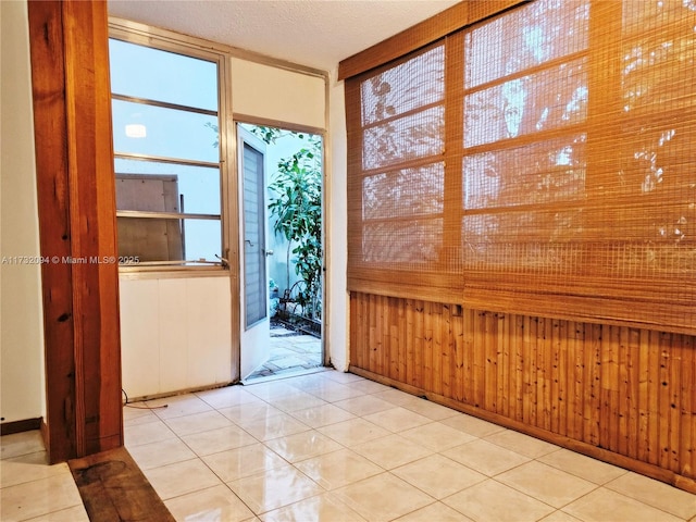 interior space featuring wooden walls, a textured ceiling, and tile patterned floors