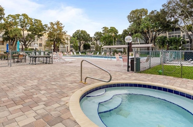 pool with fence and a hot tub