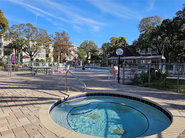 view of swimming pool featuring fence and a hot tub