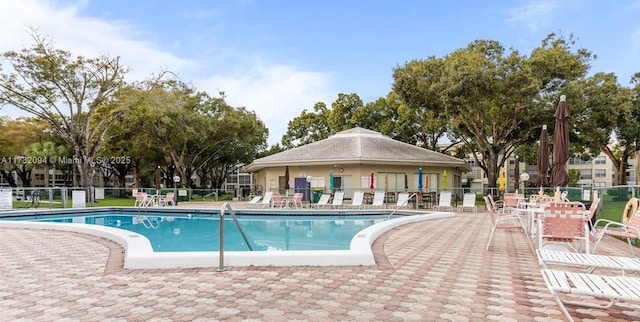 community pool with a patio area and fence